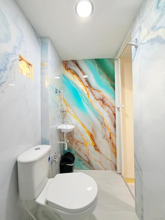 a bathroom with a toilet and a painting on the wall at Hotel San Vicente in Medellín