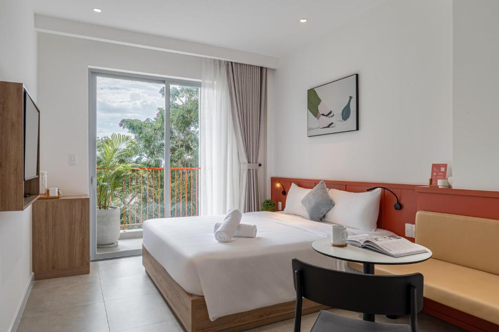 a bedroom with a bed and a table and a window at COMMON INN Thu Dau Mot in Ga Phú Văn