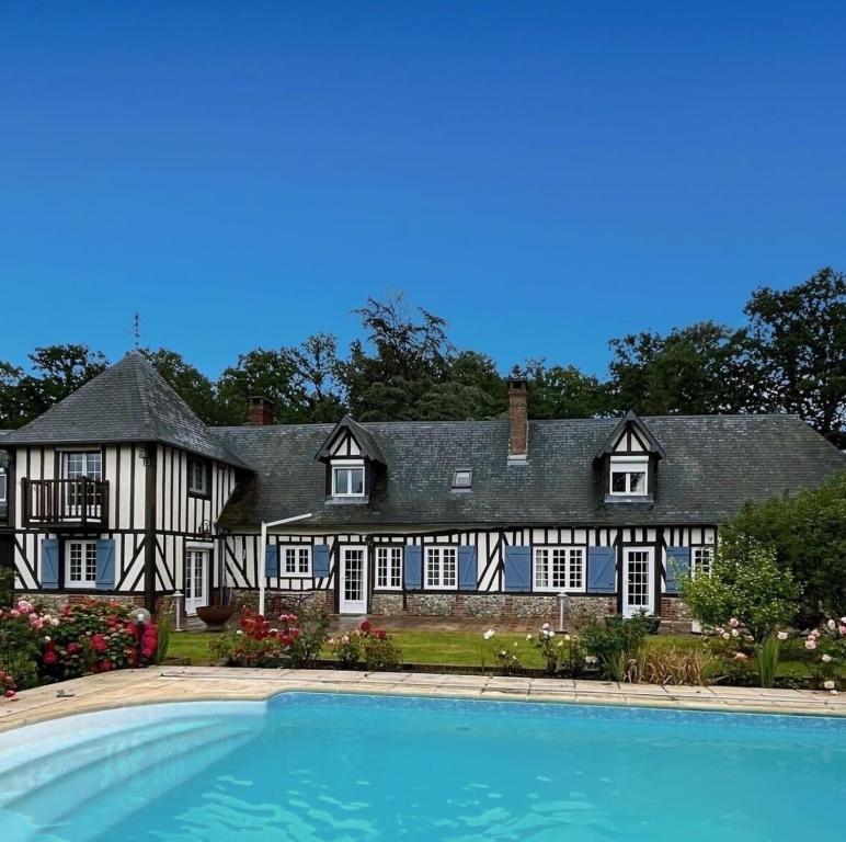 eine Außenansicht eines großen Hauses mit Swimmingpool in der Unterkunft Harmony Homes Le Cottage Bleu - Indoor Pool Sauna & Spa in Le Planquay