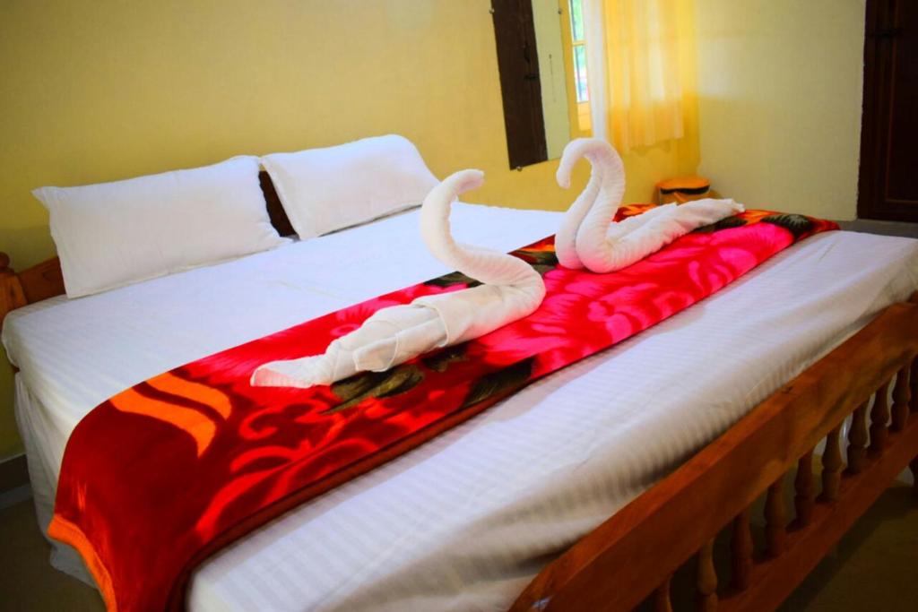 two swans on a bed with a red and white blanket at Divine home stays in Madikeri