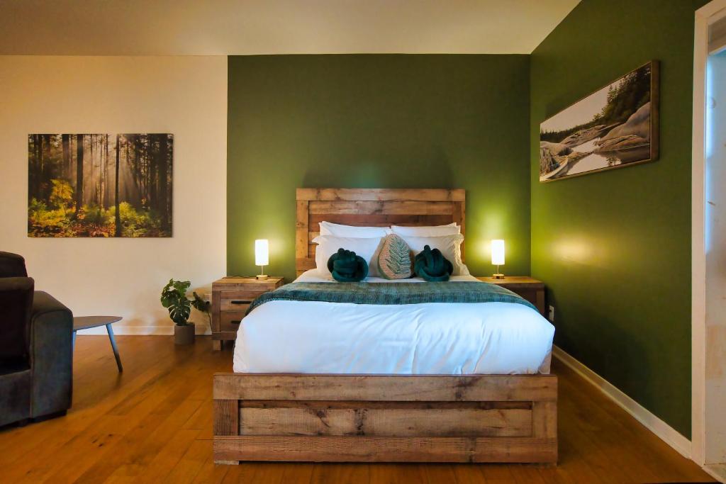 a bedroom with a bed and a green wall at Condo Hôtel Magog Orford in Orford
