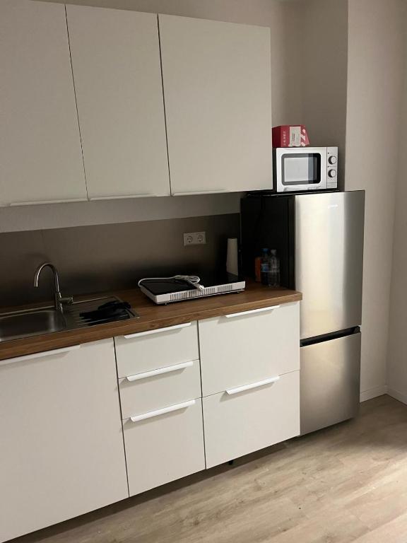 eine Küche mit weißen Schränken und einem Edelstahlkühlschrank in der Unterkunft Apartment in einem ehemaligen Hotel in Stuttgart