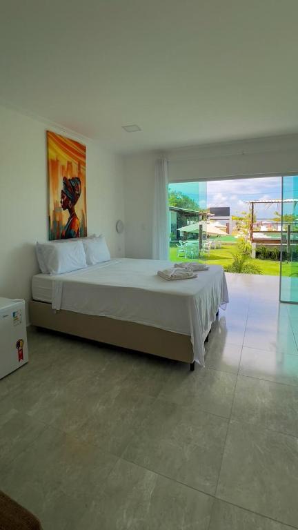 a bedroom with a large bed and a large window at Mambo beach gamboa in Cairu
