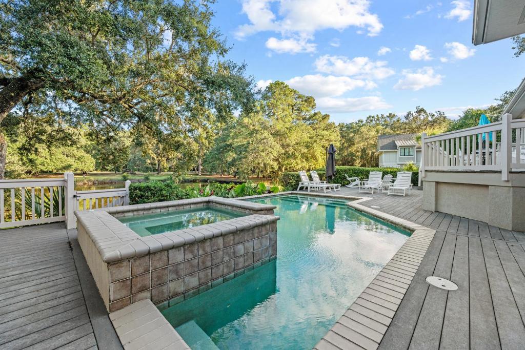 a swimming pool on a wooden deck next to a house at Cane Current in Hilton Head Island