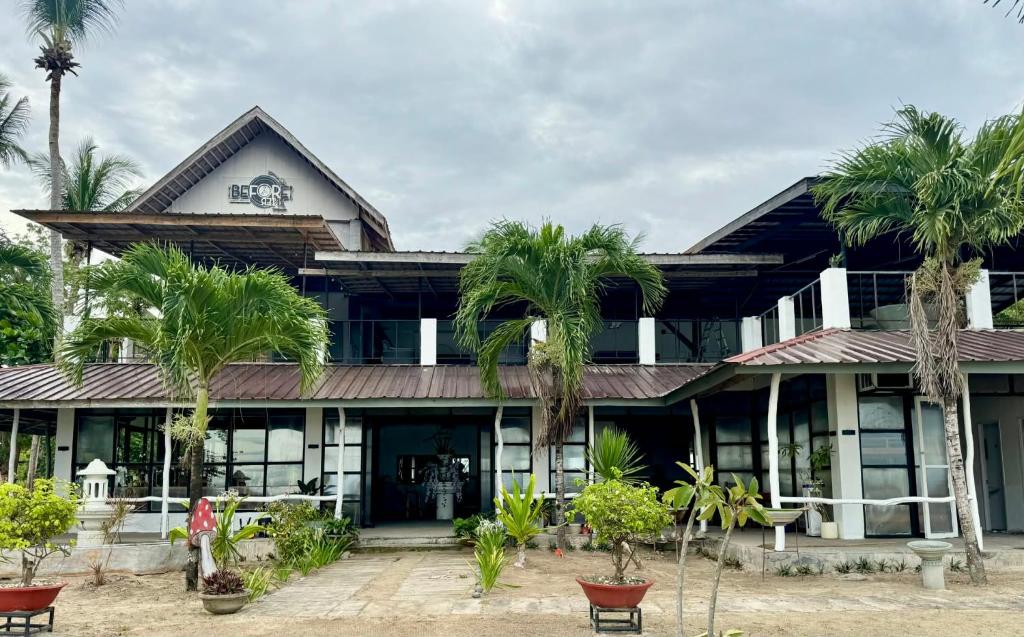 Un edificio con palmeras delante. en Puerto Paraiso Hostel, en Puerto Princesa
