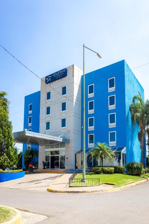 ein blaues Gebäude mit einer Palme davor in der Unterkunft Hotel Galerías Express in Tepatitlán