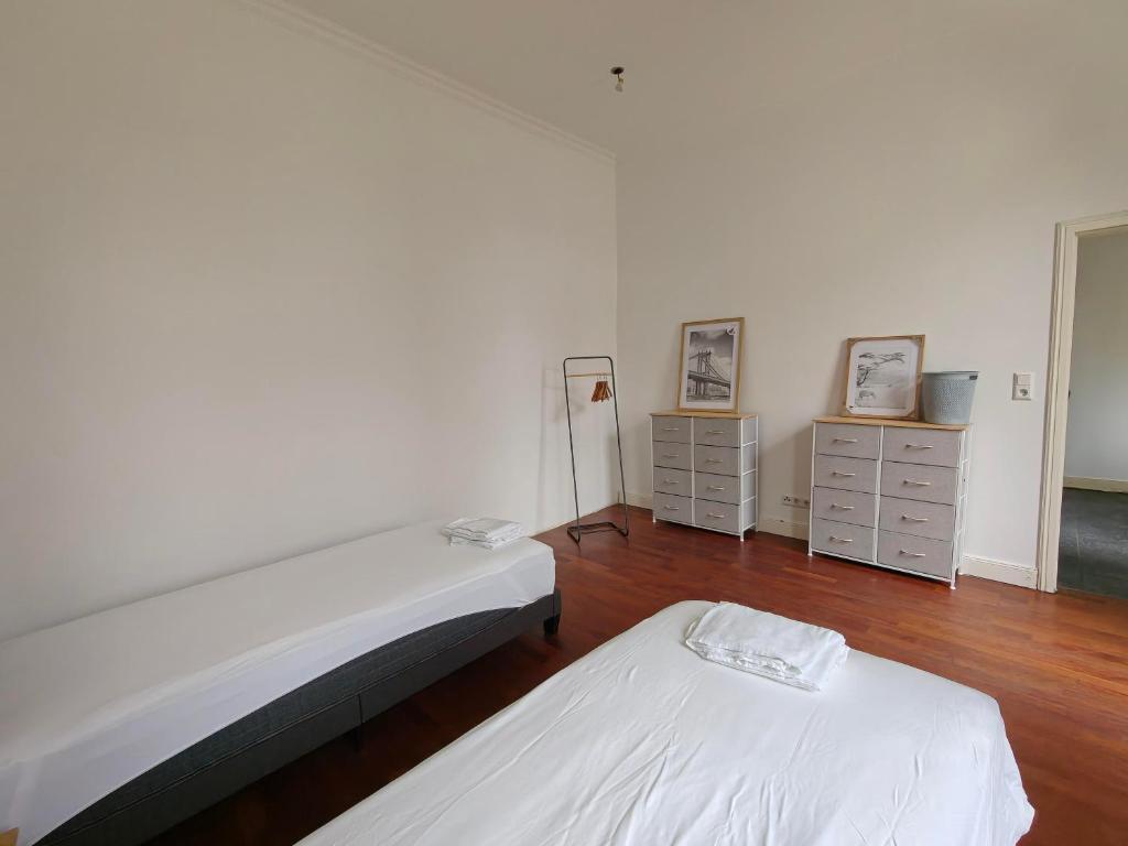 Cette chambre blanche dispose de 2 lits et de parquet. dans l'établissement Schiefe Stadtvilla Oldenburg - großes Altbauhaus, à Oldenbourg