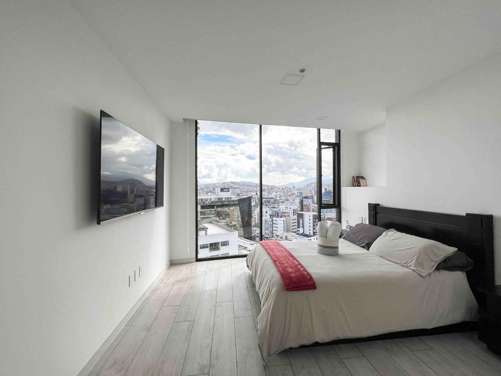 キトにあるSuite Piso 17 - Increible Vista - Agua filtrada ilimitadaのベッドと大きな窓のある寝室