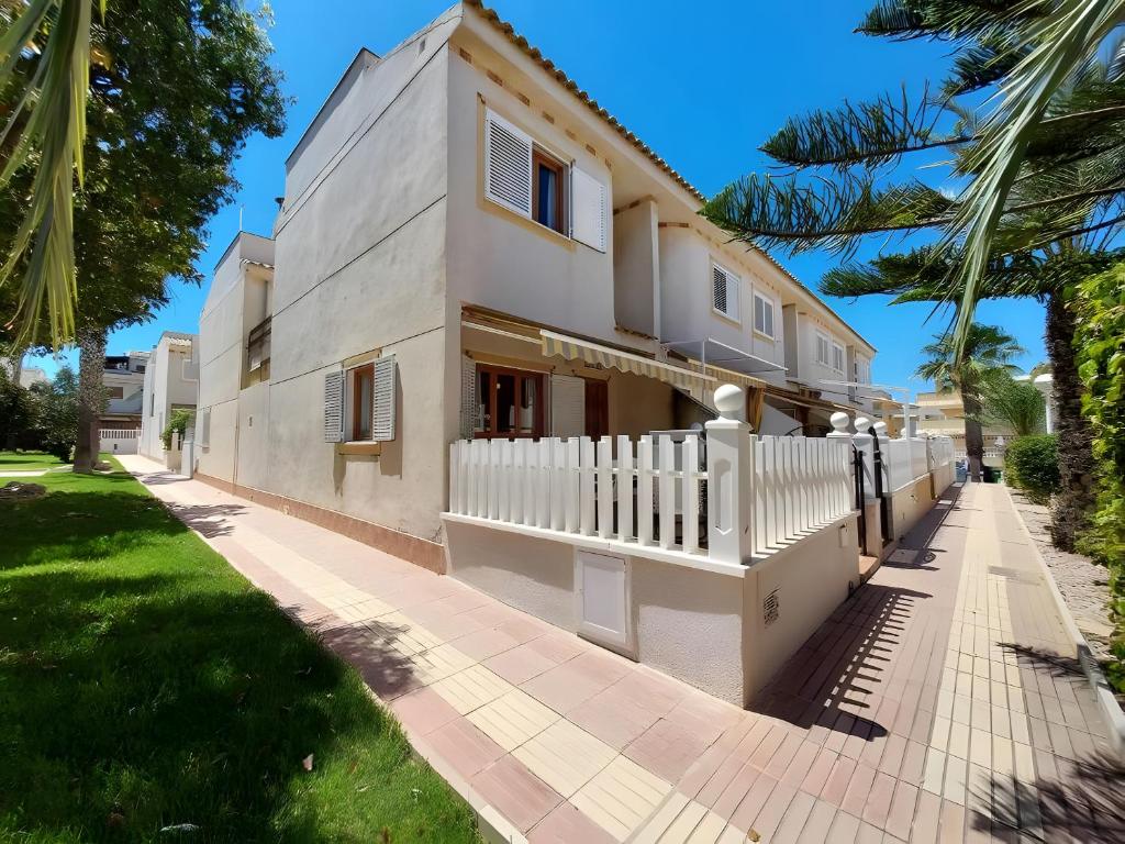 een huis met een wit hek en palmbomen bij Manuel 217 en Gran Alacant in Gran Alacant