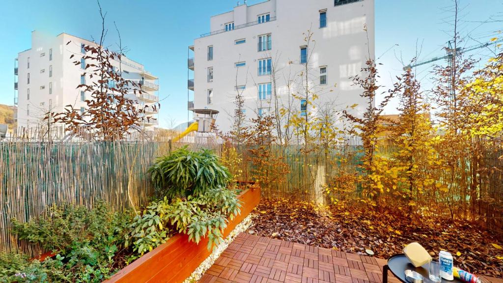 a wooden bench in a garden with a building at 3unity Apartment Kamence in Kysucké Nové Mesto