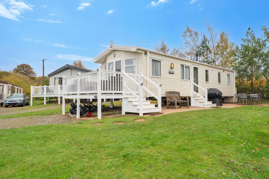 a mobile home with a porch and a yard at Vacant Nests The Archerfield Seton Sands in Longniddry