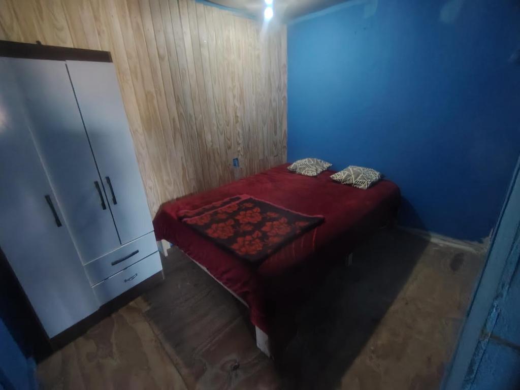 Un pequeño dormitorio con una cama roja y un armario en Cabaña Marina 1530, en Viña del Mar