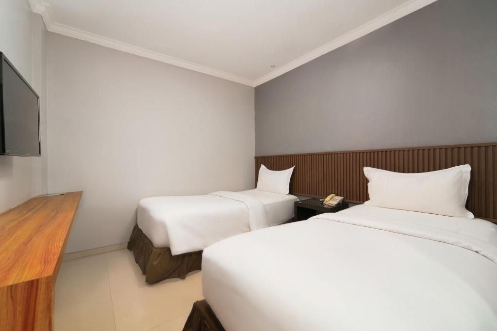 a hotel room with two beds and a flat screen tv at Barelang Hotel Nagoya Batam in Nagoya