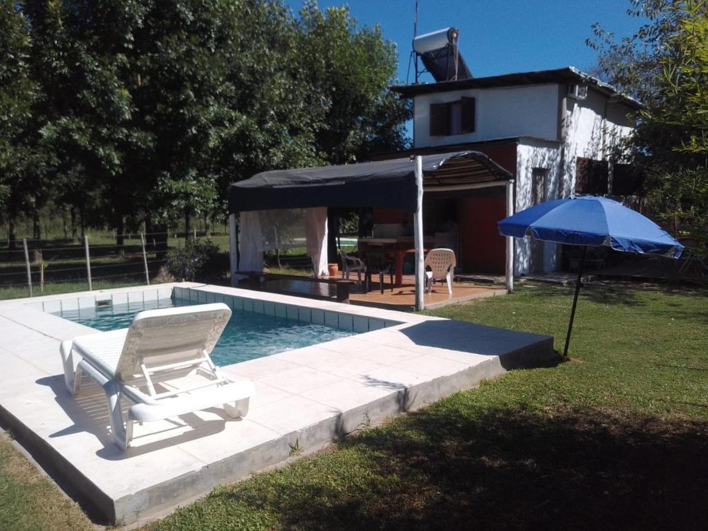 a chair and an umbrella next to a swimming pool at El Nido in Sauce Viejo
