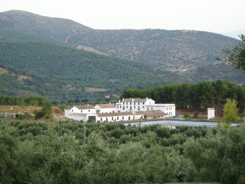 a large white building with mountains in the background at Cortijo de Bornos in Cambil