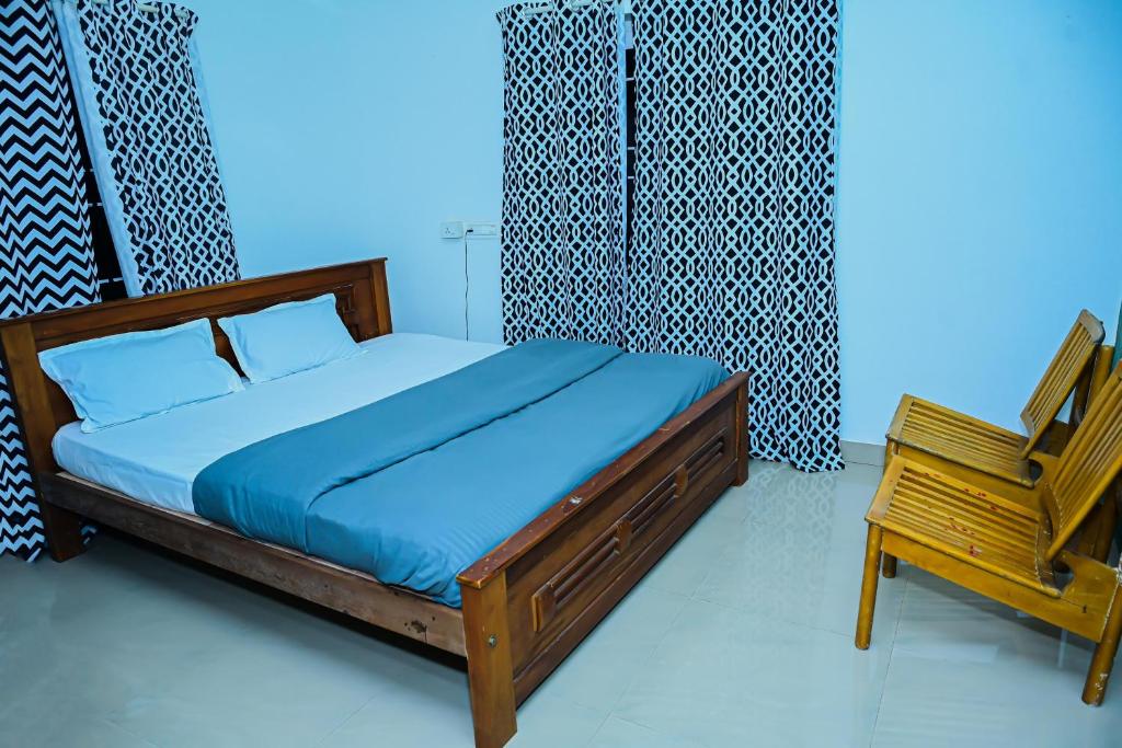 a bedroom with a bed and a wooden chair at KK Residences in Madikeri