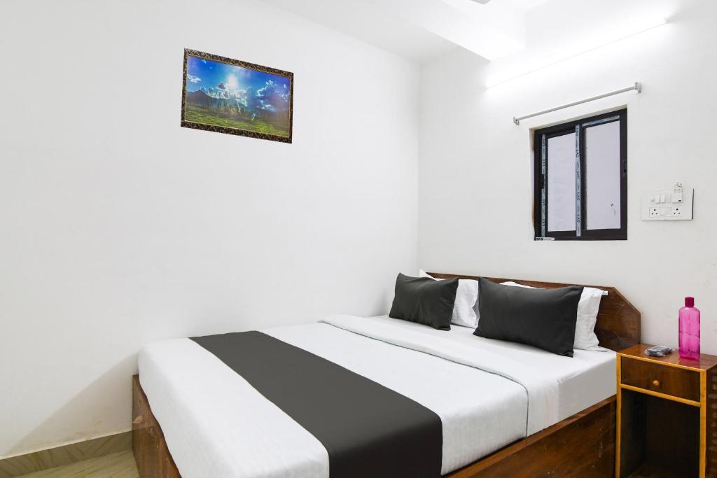 a bedroom with a bed with white walls and a window at HOTEL O SP in Kolkata