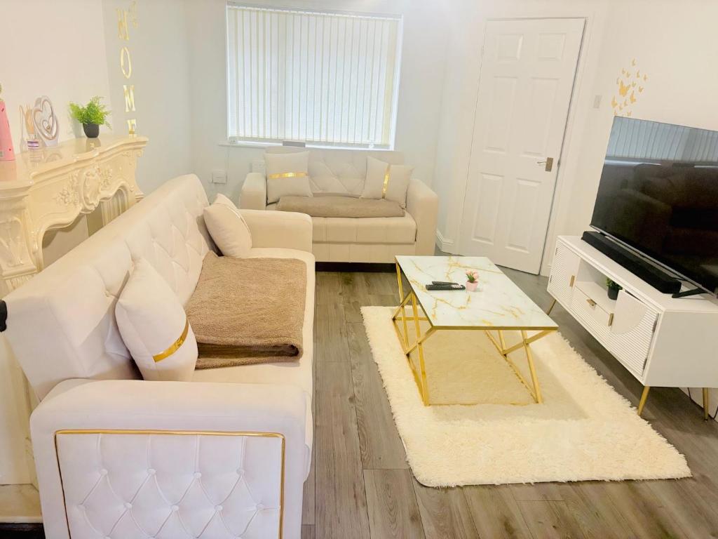a living room with a white couch and a television at Goodness homes in Manchester