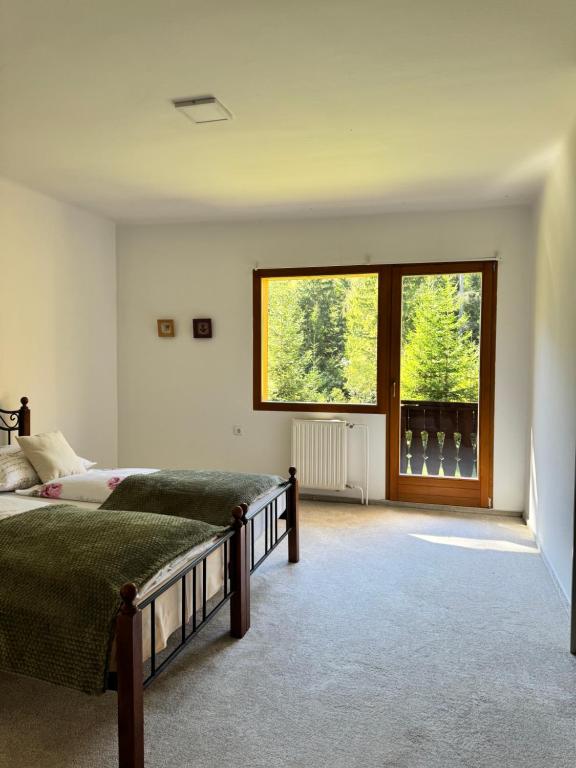 a bedroom with two beds and a large window at Cozy Mountain Stay near Kranjska Gora in Gozd Martuljek