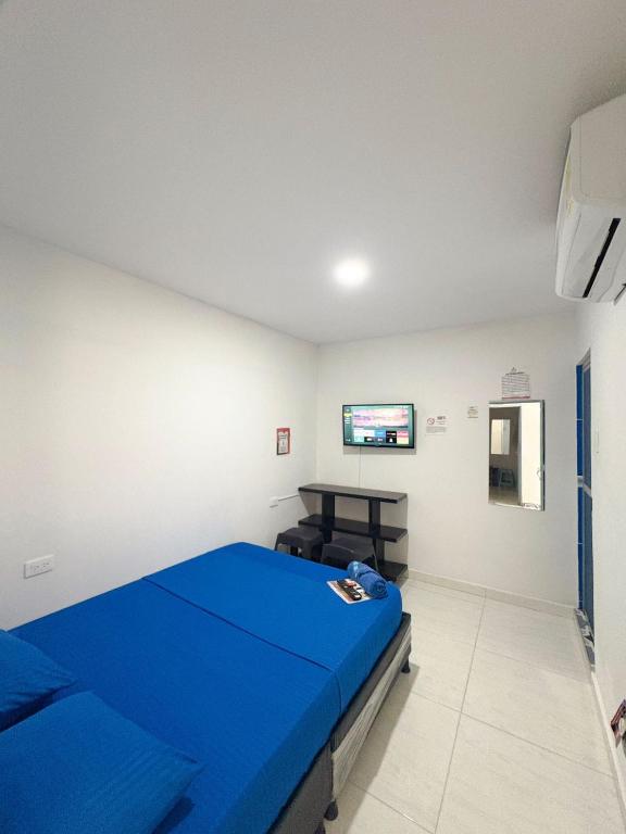 ein Schlafzimmer mit einem blauen Bett und einem Fernseher in der Unterkunft Hotel 7 in Cúcuta