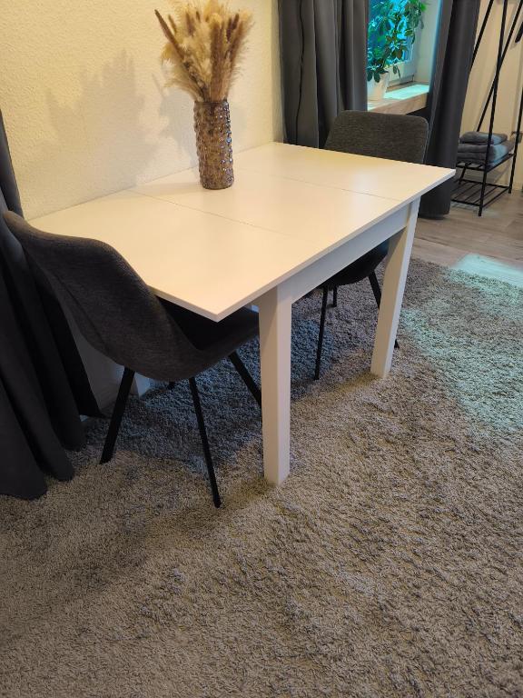 a white table with two chairs and a vase on it at Studio am Waldrand in Bad Hersfeld