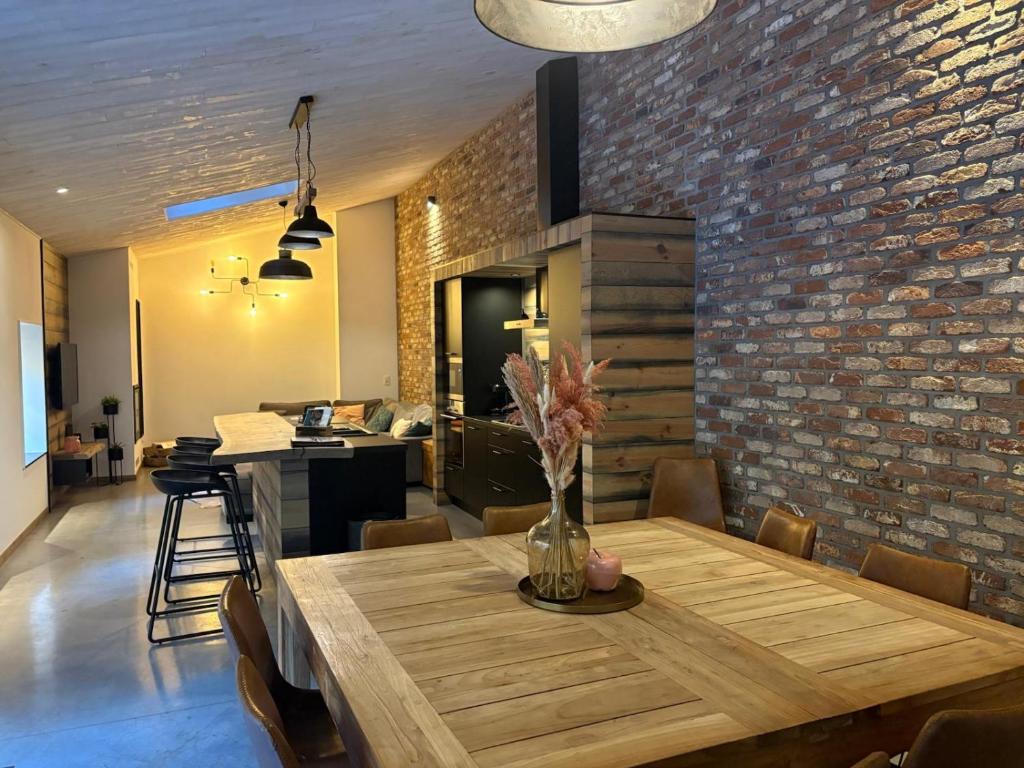 a dining room with a wooden table and a brick wall at Le Gîte des Platanes in Spa