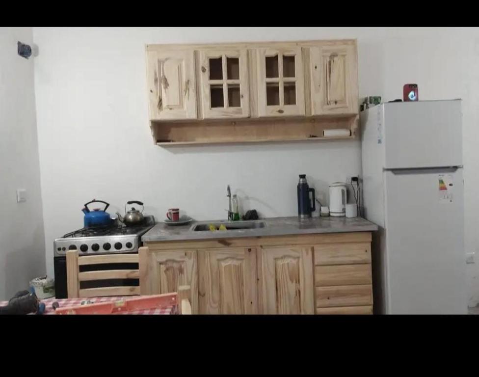 a kitchen with wooden cabinets and a white refrigerator at Casa mar del tuyu in Mar del Tuyú
