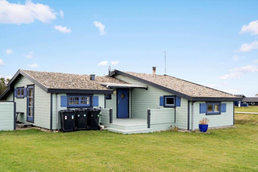 een klein huis met een blauwe deur op een erf bij 1069-Thisted-Kobbelsti-23 in Klitmøller