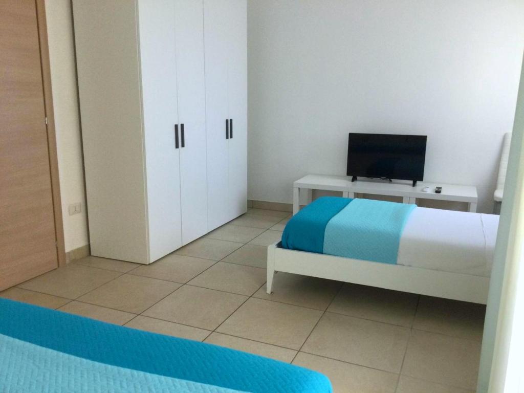 een slaapkamer met een bed en een bureau met een televisie bij Sunny House Fourteen in Assemini