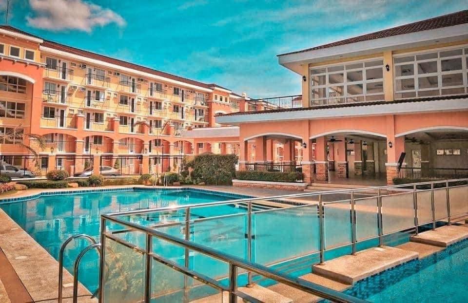 a hotel with a swimming pool in front of a building at Rafaels Staycation at Arezzo in Davao City