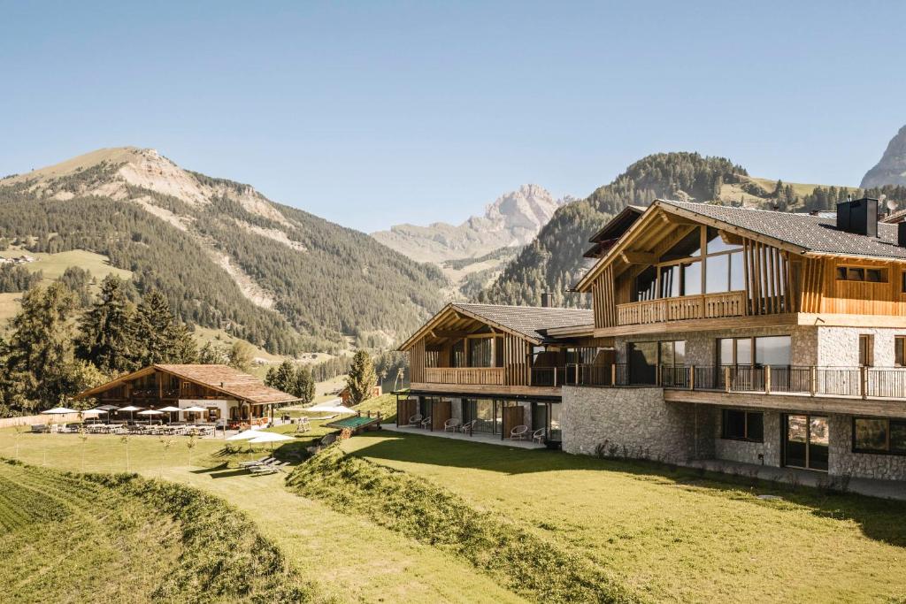 a house on a hill with mountains in the background at Muliné Lodge in Selva di Val Gardena