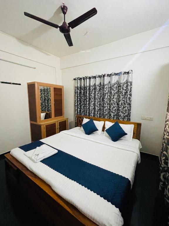 a bedroom with a large bed with a ceiling fan at Vythiri saara inn in Vythiri