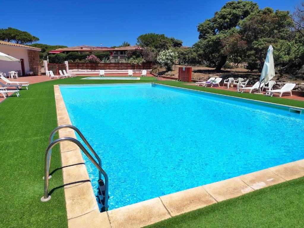 een zwembad in een tuin met stoelen en parasols bij Welcome to Portoscuso in Portoscuso