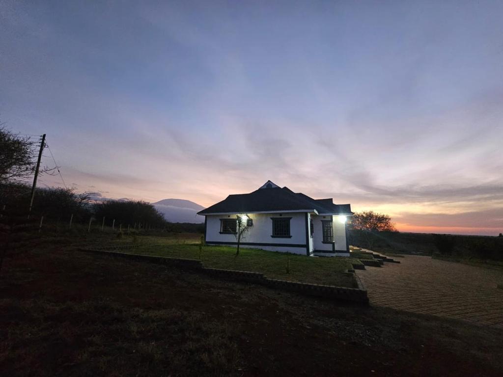 a small white house with lights in a field at Andu Kuboiye Homes in Kimana