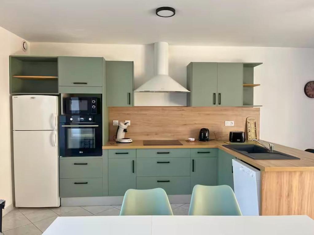 a kitchen with green cabinets and a white refrigerator at Maison Centre Ville - Saint-James in Saint-James