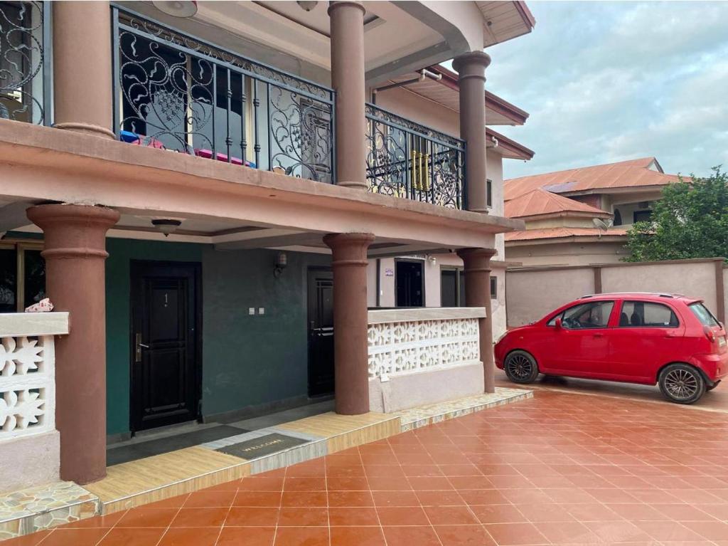 a red car parked in front of a house at ODeTTe GUEST HOUSE in Kumasi