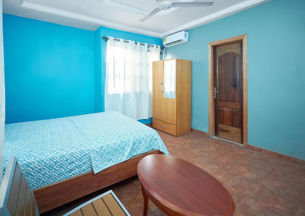 a blue bedroom with a bed and a wooden cabinet at ODeTTe GUEST HOUSE in Kumasi