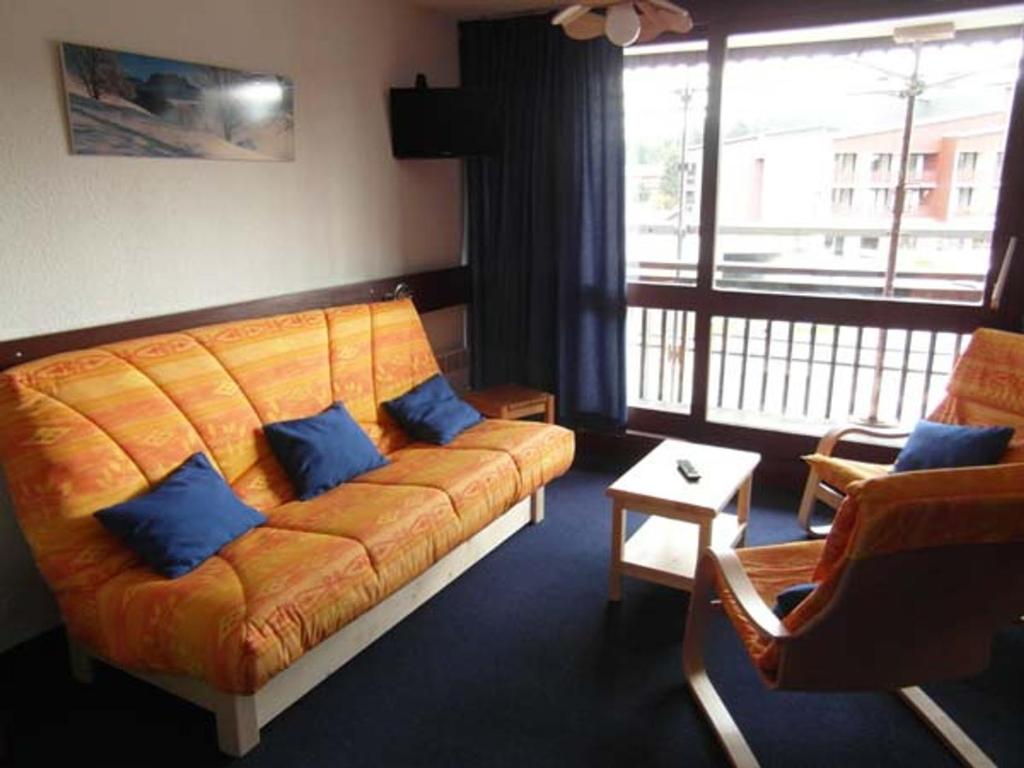 ein Wohnzimmer mit einem orangenen Sofa und blauen Kissen in der Unterkunft Appartement cosy au Praz de Lys pour 6 pers, près des pistes, 2 pièces - FR-1-815-20 in Le Praz de Lys