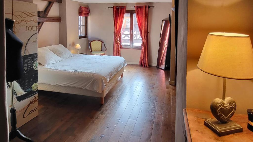 een slaapkamer met een bed, een lamp en een raam bij La Tour de la Chapelle - Parking privé in Obernai