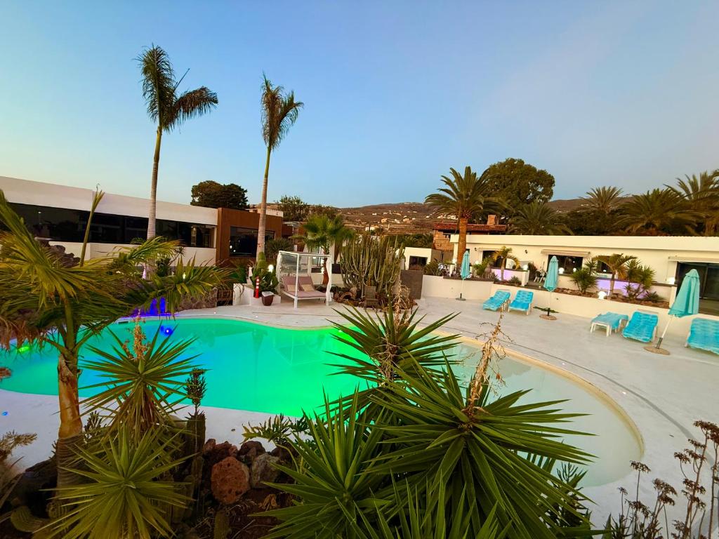 a swimming pool with palm trees and a building at Paraiso villas in Playa Paraiso