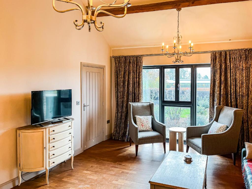 a living room with a flat screen tv and chairs at Valentines Cottage - Uk48509 in Kirk Hammerton