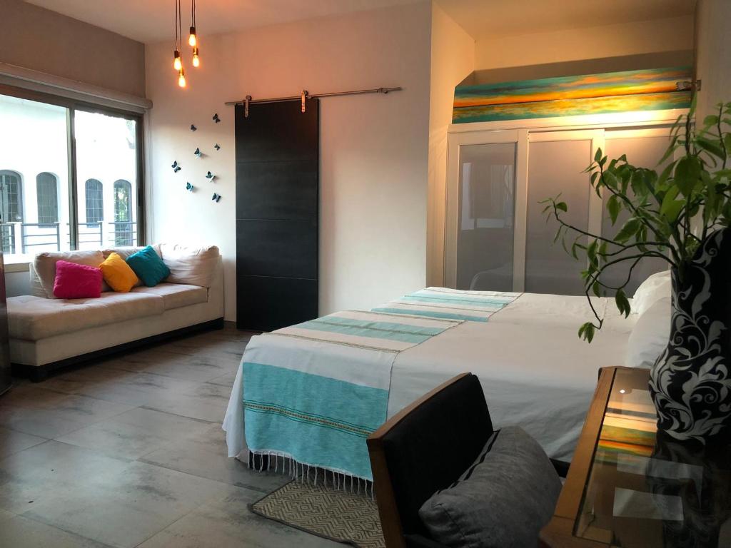 een slaapkamer met een bed en een bank bij Casa Arbol de Paz in Chacala