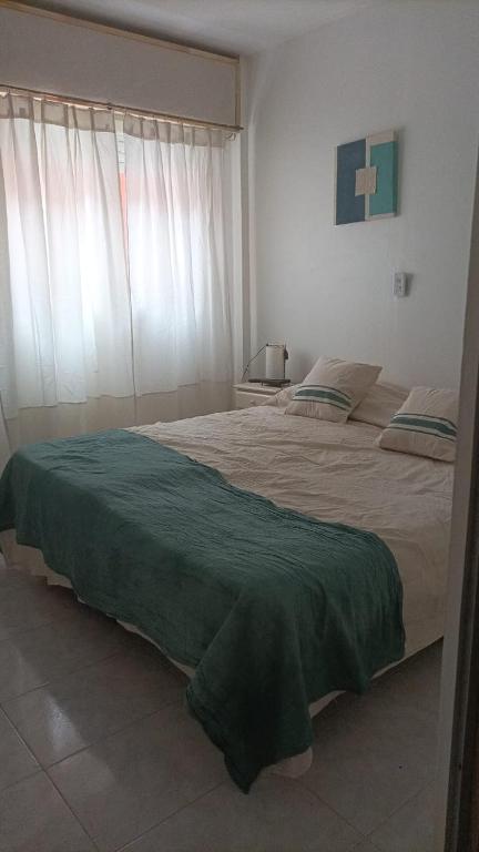 a bedroom with a large bed with a green blanket at Departamento Romalu in Santa Teresita