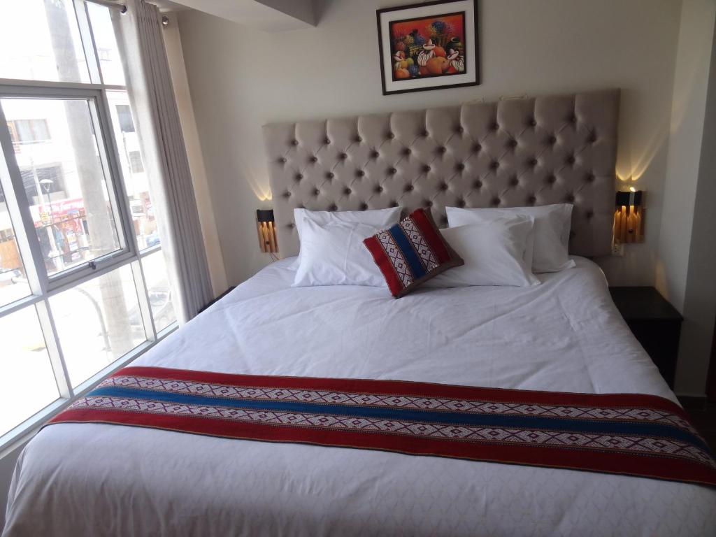 a bedroom with a large bed with a large window at Hotel Inka House Chinchero in Chinchero