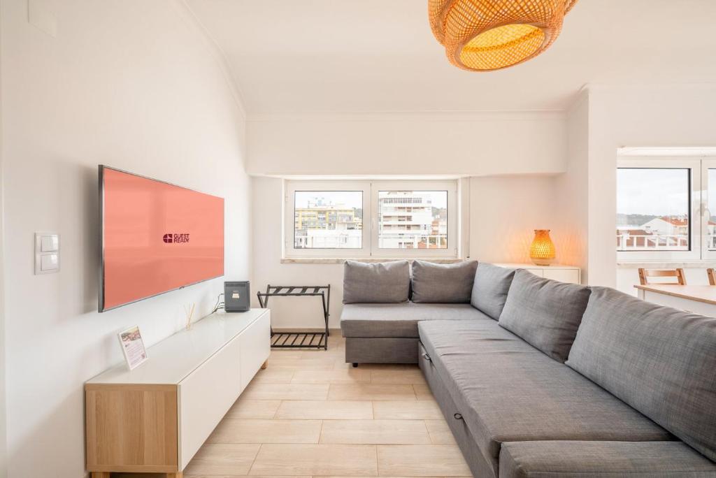 a living room with a couch and a flat screen tv at GuestReady - Sunny Retreat in Costa da Caparica in Costa da Caparica