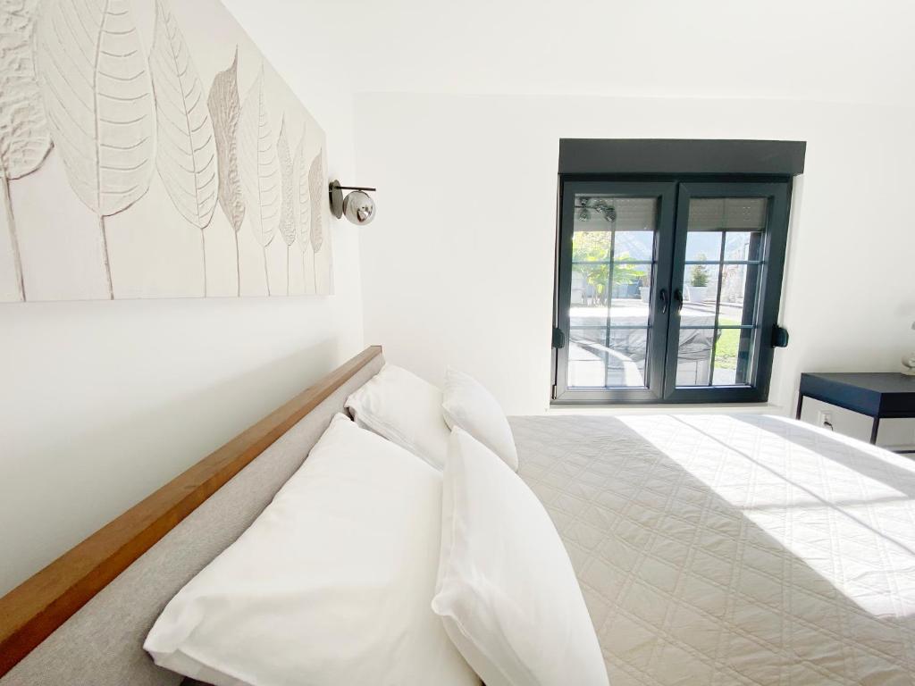 een witte slaapkamer met een bed en een raam bij Petite Mansion in Nasicz