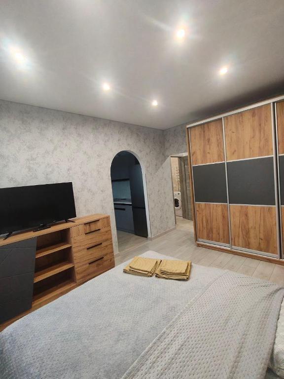 ein Schlafzimmer mit einem großen Bett und einem Flachbildfernseher in der Unterkunft New Comfort Apartment in Hostomelʼ