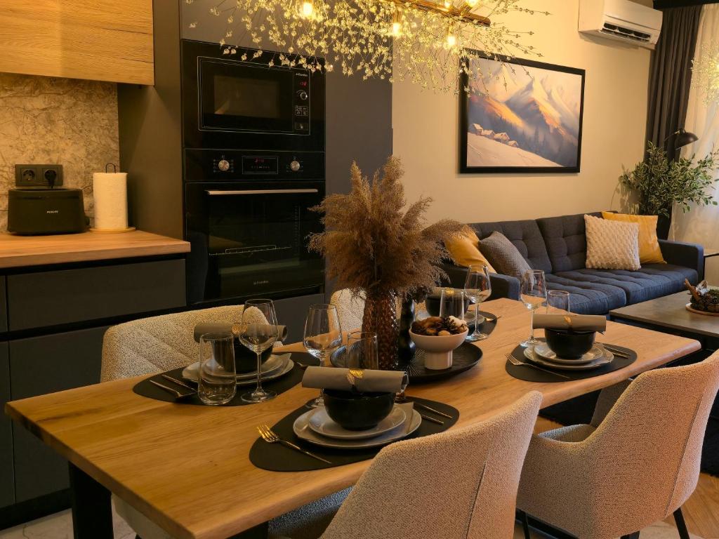 eine Küche und ein Wohnzimmer mit einem Holztisch mit Stühlen in der Unterkunft LUXURY Designer Apt I Meters to Gondola Lift I Sleeps 6 I Pool & Parking I in Bansko