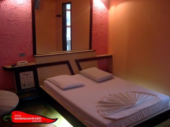 Un dormitorio con una cama con un espejo en la pared. en Signus 2, en Belo Horizonte