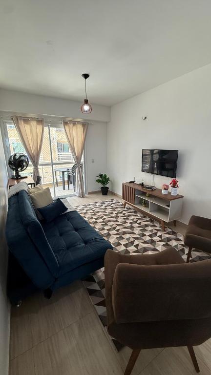 a living room with a blue couch and a tv at Beach Place ACONCHEGO e refúgio perto do mar in Cumbuco